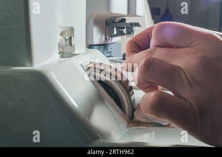 Un uomo affina un ago metallico su una mola. Primo piano della mano maestra Foto Stock