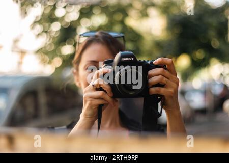 Ragazza con fotocamera Canon in riflesso a specchio. Donna che scatta foto allo specchio. Concetto di hobby. Stile di vita di strada. Giovane fotografa. Vita quotidiana. Foto Stock