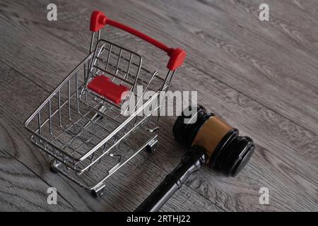 Immagine ravvicinata del martelletto del giudice e del carrello della spesa sul tavolo. Diritti dei consumatori, protezione dei clienti, concetto di diritto commerciale Foto Stock