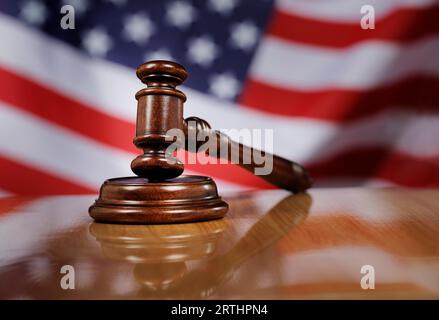 Martelletto in legno di mogano su un tavolo in legno lucido, bandiera USA sullo sfondo Foto Stock
