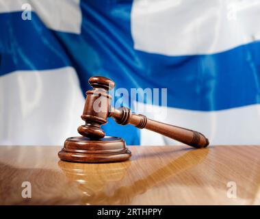 Martelletto in legno di mogano su un tavolo in legno lucido, bandiera della Finlandia sullo sfondo Foto Stock