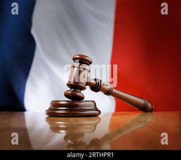 Martelletto in legno di mogano su un tavolo in legno lucido, bandiera della Francia sullo sfondo Foto Stock