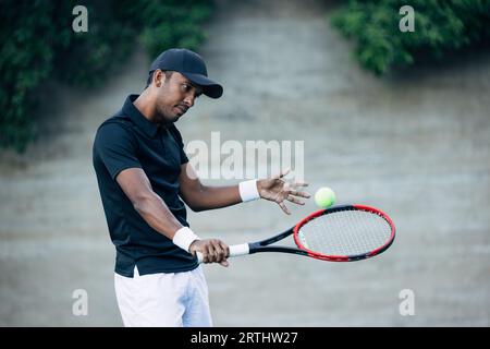 Giocatore di tennis che restituisce la palla mentre si pratica all'aperto Foto Stock