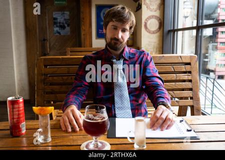 Un uomo disoccupato solitario beve alcolici in un bar. Il concetto di alcolismo Foto Stock