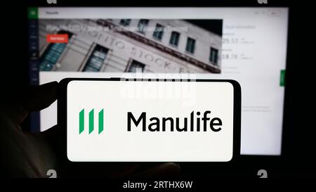 Persona che possiede un telefono cellulare con il logo della società canadese Manulife Financial Corporation sullo schermo davanti alla pagina Web. Concentrarsi sul display del telefono. Foto Stock