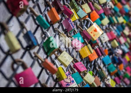 Lucchetti colorati con nomi e date incriminate rappresentano l'amore su una recinzione Foto Stock