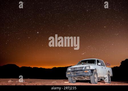 Osservazione delle stelle nel deserto di Wadi Rum in Giordania. Dozzine di campi Beduin offrono tour in camion e alloggi turistici nel deserto sotto il cielo sereno Foto Stock