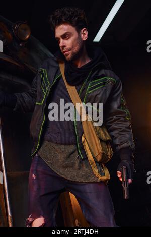 un uomo cupo e scaltro con un abito indossato, con pistola e borsa in tela nella metropolitana abbandonata Foto Stock