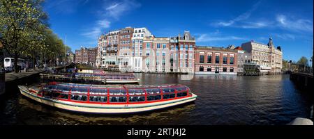 Le navi turistiche della città sono ancorate all'Amstel di Amsterdam, Paesi Bassi in primavera. Navi da visita della città ancorate sull'Amstel ad Amsterdam, Paesi Bassi in Foto Stock