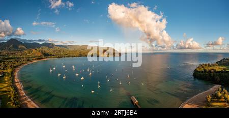 Vista aerea dell'arcobaleno e delle nuvole illuminate dal sole sulle cime delle montagne della costa di Na Pali attraverso la baia di Hanalei a Kauai Foto Stock