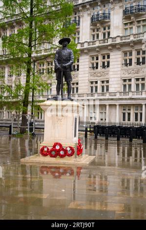 LONDRA - 24 aprile 2023: La statua del soldato Gurkha si erge tra le corone rosse di papavero all'esterno del Ministero della difesa, con terreno umido riflettente che aggiunge t Foto Stock