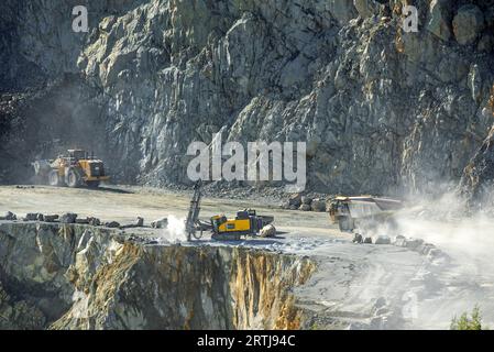 Carro di perforazione di superficie, bulldozer e dumper da trasporto in cava di porfido, miniera a cielo aperto per ghiaia per la costruzione di strade a Lessines, Hainaut, Belgio Foto Stock