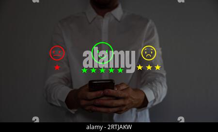 Mano dell'acquirente toccando lo schermo virtuale sull'icona Happy Smile Face per il feedback di valutazione rivedere l'opinione di soddisfazione e la testimonianza. Cliente. Foto Stock