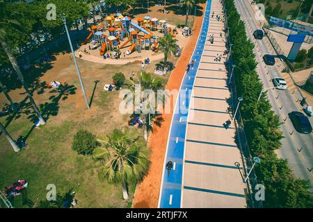 Parco giochi per bambini, pista ciclabile e passerella sull'argine. Vista aerea delle palme, del passaggio pedonale e della pista ciclabile Foto Stock