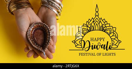 Lunga bandiera per Happy Diwali con mani femminili che reggono una lampada a olio Foto Stock