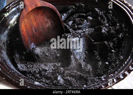 Preparazione della talpa rossa, un tipico piatto messicano in una pentola di argilla con un gigantesco cucchiaio di legno sul fuoco di una stufa con tutti gli ingredienti integrati Foto Stock