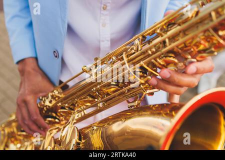 Vista da concerto del sassofonista in costume blu e bianco, sax con cantante e gruppo musicale durante lo spettacolo dell'orchestra jazz che esegue musica Foto Stock