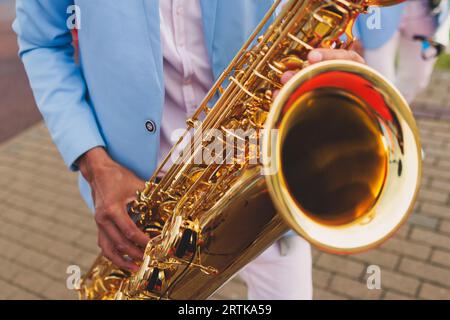 Vista da concerto del sassofonista in costume blu e bianco, sax con cantante e gruppo musicale durante lo spettacolo dell'orchestra jazz che esegue musica Foto Stock