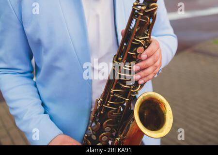 Vista da concerto del sassofonista in costume blu e bianco, sax con cantante e gruppo musicale durante lo spettacolo dell'orchestra jazz che esegue musica Foto Stock