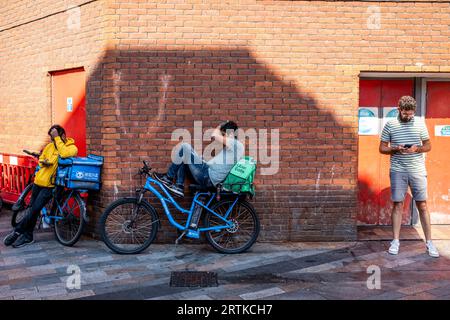 I ciclisti che effettuano consegne di cibo fanno una pausa a Chinatown, Soho, Londra, Regno Unito. Foto Stock