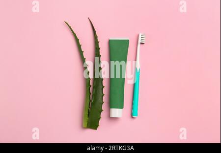 Tubo di dentifricio, spazzolino da denti e aloe fresca su sfondo rosa, disteso Foto Stock