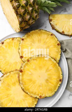 Fette di gustoso ananas maturo su un tavolo in marmo bianco, piatto Foto Stock