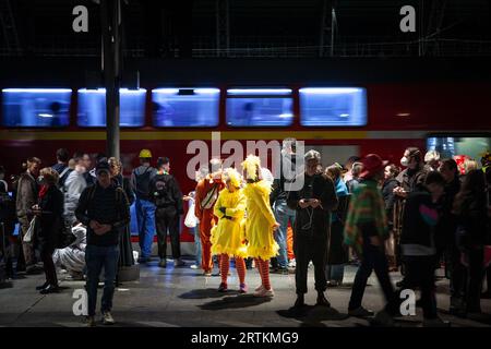 Foto di persone vestite in costume per il Carnevale di Colonia in piedi sulla piattaforma di Koln Hbf, con un accento su un uomo vestito come una guardia che usa la h Foto Stock