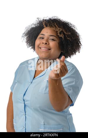 giovane infermiera latina afro indossa un'uniforme blu, sorridente che fa il cuore con le dita e guarda la fotocamera, l'immagine verticale, le persone e lui Foto Stock