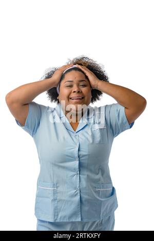 giovane donna latina afro con uniforme medica blu in piedi che mostra come mette la cravatta di capelli sulla testa, sorridendo e guardando la macchina fotografica, concetto di medicina Foto Stock