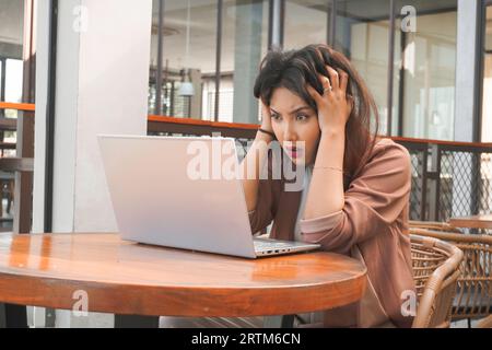 Un ritratto di donna d'affari asiatica sembra stressato e depresso mentre lavora in caffetteria Foto Stock