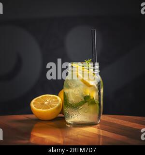 Acqua al limone, limonata in vaso. Tagliare i limoni sullo sfondo. Limonata naturale. Foto Stock