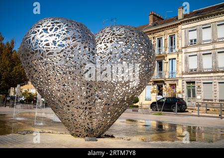 La scultura conosciuta come il "cuore di Troyes", accanto a una fontana d'acqua e alle tradizionali case cittadine di Troyes, Aube, Francia. Foto Stock