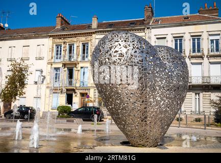 La scultura conosciuta come il "cuore di Troyes", accanto a una fontana d'acqua e alle tradizionali case cittadine di Troyes, Aube, Francia. Foto Stock