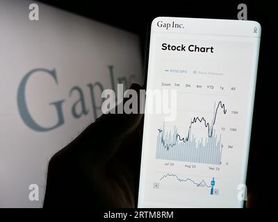 Persona che tiene il cellulare con il sito Web dell'azienda statunitense di abbigliamento e accessori Gap Inc. Sullo schermo con logo. Concentrarsi sul centro del display del telefono. Foto Stock