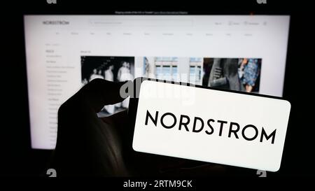 Persona che possiede uno smartphone con il logo della società statunitense Nordstrom Inc. Sullo schermo di fronte al sito Web. Concentrarsi sul display del telefono. Foto Stock