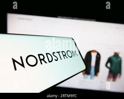 Telefono cellulare con logo della società americana Nordstrom Inc. Sullo schermo davanti al sito Web. Mettere a fuoco il display centrale sinistro del telefono. Foto Stock