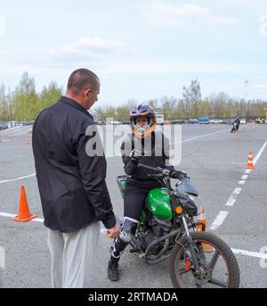 Una giovane donna sta imparando a guidare una moto in una scuola di motociclette. Lei è insegnata da un insegnante Foto Stock