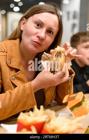 Ivano-Frankivsk, Ucraina 7 giugno 2023: Una giovane ragazza mangia un hamburger al McDonald's, un fast food. Foto Stock