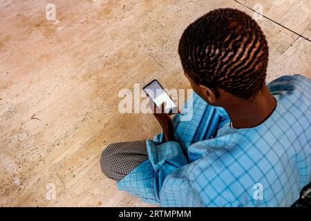 Musulmano che legge scritture coraniche sul suo cellulare nella grande moschea di Touba, in Senegal Foto Stock