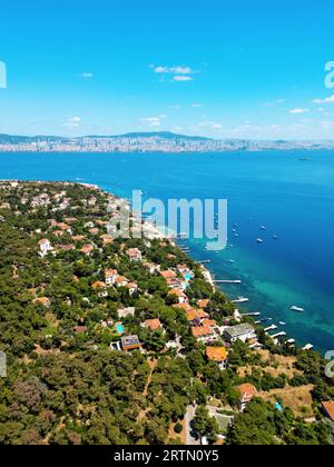 Vista aerea con droni di Kinaliada, Turchia. Edifici residenziali situati sulla riva del mare di Marmara, Istanbul in lontananza Foto Stock