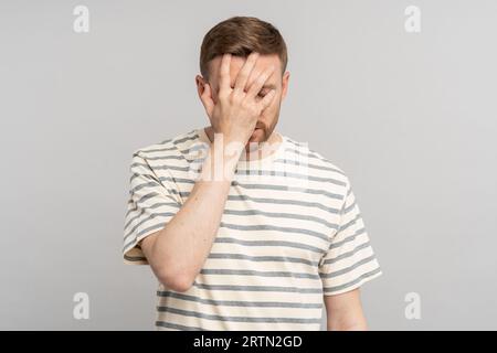 Deluso e stressato maschio di mezza età che fa gesto di palma facciale con la mano che si incolpa per errore Foto Stock