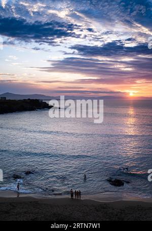 Paesaggio in formato verticale di un tramonto sul mare e di alcune persone irriconoscibili sulla spiaggia. Vista aerea. Foto Stock