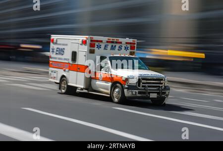 Un'ambulanza che corre attraverso Una Downtown City Street, con Motion Blur Foto Stock