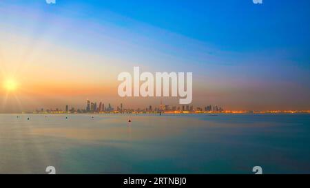 Vista dello skyline del Kuwait - con il più famoso punto di riferimento della città di Kuwait - durante l'alba Foto Stock