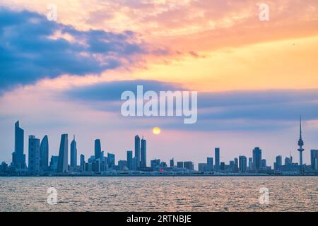 Vista dello skyline del Kuwait - con il più famoso punto di riferimento della città di Kuwait - durante il tramonto Foto Stock