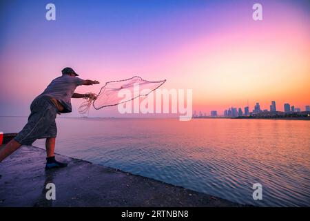 Kuwait City 01112022: Lo skyline del Kuwait con il punto di riferimento più famoso della pesca con la persona dal ponte sulla spiaggia Foto Stock