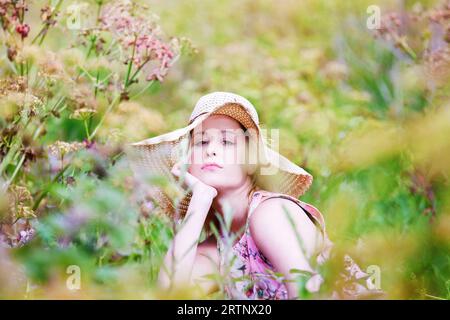 giovane donna che posa in campo con fiori rosa Foto Stock