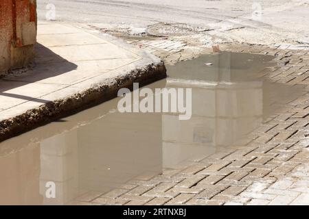 L'Avana, Cuba - 30 agosto 2023: Una pozza d'acqua stagnante in una strada acciottolata Foto Stock