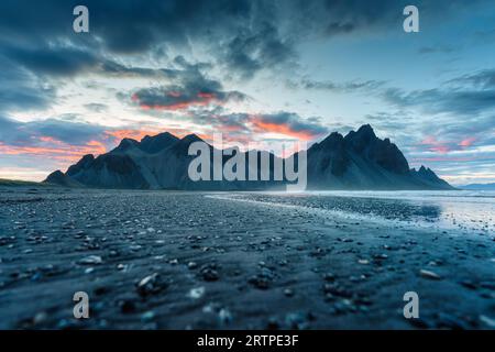 Suggestivo paesaggio del cielo al tramonto sulla montagna Vestrahorn sulla spiaggia di sabbia nera in estate nella penisola di Stokksnes, Islanda Foto Stock