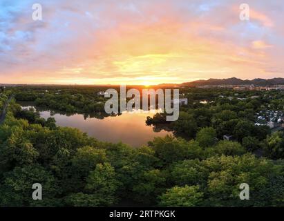 Hangzhou. 31 luglio 2023. Questa foto aerea scattata il 31 luglio 2023 mostra la zona umida di Xixi all'alba a Hangzhou, nella provincia di Zhejiang nella Cina orientale. I diciannovesimi Giochi asiatici si svolgeranno a Hangzhou tra il 23 settembre e l'8 ottobre, con un totale di 40 sport. Saranno i terzi Giochi asiatici ad essere ospitati in Cina, dopo Pechino 1990 e Guangzhou 2010. Gli attesissimi Giochi asiatici possono contribuire ad aumentare la popolarità di Hangzhou, dove storia e modernità coesistono e promuovere ulteriormente la sua cultura. Crediti: Weng Xinyang/Xinhua/Alamy Live News Foto Stock